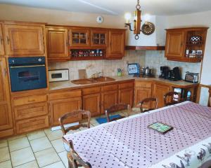 a kitchen with wooden cabinets and a table with a white table cloth at Maison en pierre au milieu du bocage in Coulouvray-Boisbenâtre +12 photos