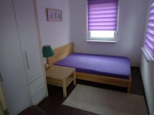 ein kleines Schlafzimmer mit einem lila Bett und einem Tisch in der Unterkunft Hermanns Teufelshütte in Betzenstein