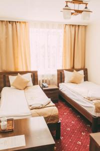 a room with two beds and a table at Dostyk Kokshetau in Kokshetau