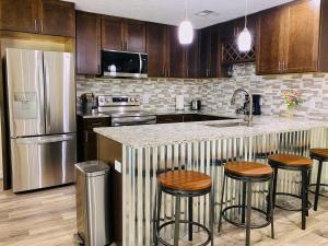 a kitchen with wooden cabinets and a counter with bar stools at 2 BR Family Friendly Nature Getaway near Golf Course in Kalamazoo