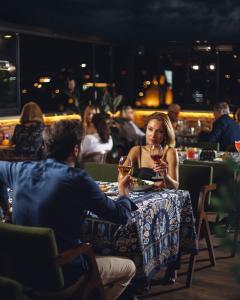 a man and woman sitting at a table with wine glasses at TbiliSee Hotel in Tbilisi City