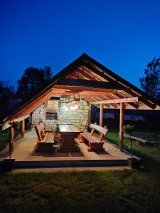 a gazebo with a picnic table and benches at Leśne zacisze-pole namiotowe in Pisklaki
