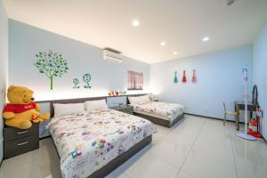 um quarto com 2 camas e um ursinho de peluche em 窩心の家民宿 em Suao