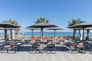 ein paar Stühle und Sonnenschirme am Strand in der Unterkunft Aquila Porto Rethymno in Rethymno