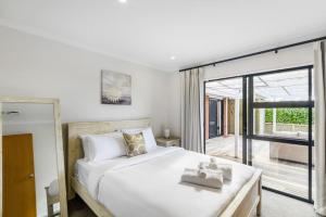 sypialnia z dużym białym łóżkiem i przesuwnymi szklanymi drzwiami w obiekcie Oasis Ode Retreat with pool and spa w Auckland