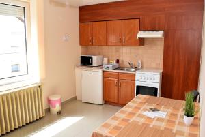uma cozinha com armários de madeira e uma mesa com um micro-ondas em Nóra apartman em Harkány