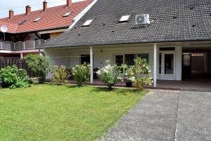 una casa con porche y un patio con plantas en Nóra apartman en Harkány