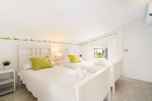 two white beds in a white bedroom with yellow pillows at S Olivera in Port d'Addaia