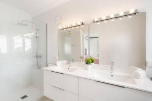 a white bathroom with two sinks and a mirror at S Olivera in Port d'Addaia