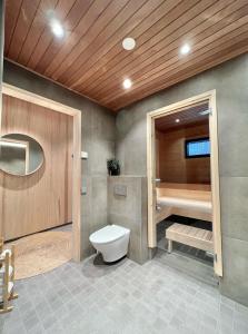 a bathroom with a toilet and a bath tub at Black Work Levi Aarni in Kittilä