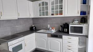 a kitchen with white cabinets and a sink and microwave at Rheinblick in Weißenthurm