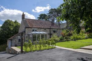 an old stone house with a greenhouse in the front yard at Church View in Nunnington