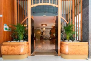 a hallway in a building with two potted plants at Continental B&B City Hotel in Bibione