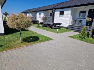 a walkway in front of a house with a bench at Fajne domki in Ustronie Morskie