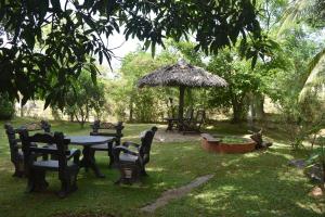 a garden with a table and chairs and an umbrella at Sigiri Dilu Villa in Sigiriya