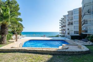 a swimming pool next to a building and the ocean at Cap Salou in Salou