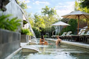 a man and a woman sitting in a swimming pool at Bali Dynasty Resort in Kuta