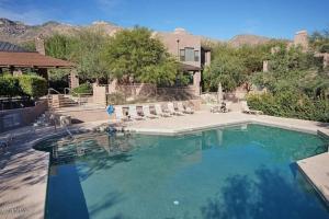une grande piscine avec des chaises et une maison dans l'établissement Gorgeous Mountain and City Views, Pools, and Hot Tubs, à Tucson
