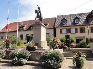 a statue in front of a building with flowers at Logement 1 à 6 personnes---Le Kelsch in Marlenheim