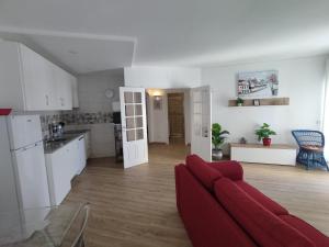 Una sala de estar con un sofá rojo y una cocina. en 7C Castelo - Casas & Papeis, en Armação de Pêra