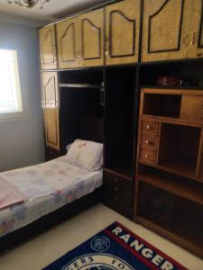 Dormitorio pequeño con cama y armarios de madera en شقة مفروشة بالتجمع الخامس, en El Cairo