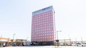 Un edificio alto con un cartel al costado. en Toyoko Inn Shin takaoka eki Shinkansen Minami guchi, en Takaoka