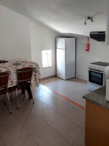 a kitchen with a table and a white refrigerator at Casa do Fundo do Povo - Serra da Estrela in Cortes do Meio