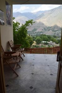 Chitral Green Guest House في شيترال: شرفة مع كراسي وإطلالة على الجبال