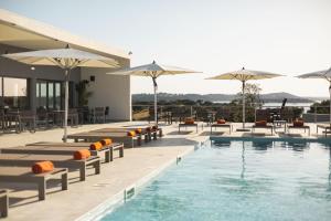 a pool with chairs and umbrellas next to a building at Herdade dos Delgados in Mourão