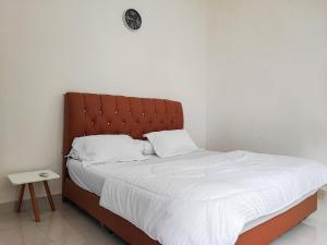 a bed with a brown headboard in a room at Adela Homestay Syariah Near Universitas Muhammadiyah Jambi Mitra RedDoorz in Jambi +1 photo