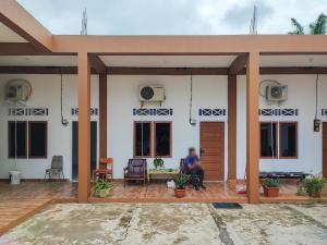 ジャンビにあるAdela Homestay Syariah Near Universitas Muhammadiyah Jambi Mitra RedDoorzの家の玄関に座る男