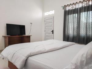 ジャンビにあるAdela Homestay Syariah Near Universitas Muhammadiyah Jambi Mitra RedDoorzのベッドと薄型テレビのある寝室