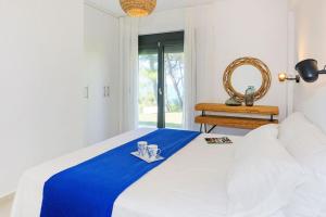 a white bed with a blue blanket and a mirror at Dilean luxury villa in Vourvourou