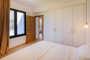 a white bedroom with a large bed and a window at Dilean luxury villa in Vourvourou