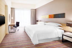 a hotel room with a large white bed and a desk at Four Points by Sheraton Puchong in Puchong