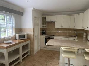 a kitchen with white cabinets and a counter with a microwave at Spacious 1 bed bungalow located on a Gower Sheep Farm in Swansea