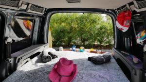 Una cama en la parte trasera de una furgoneta con un sombrero rosa en EndlessCamperVan en San Miguel de Abona