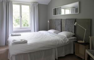 a bedroom with a white bed with a mirror at Skeviks Gård in Gustavsberg