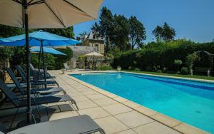 a swimming pool with chairs and umbrellas next to it at Chateau de la Vigne in Concourson-sur-Layon