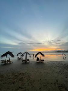 a group of picnic tables on a beach at sunset at The Yard Hiriketiya in Hiriketiya