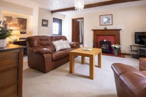 a living room with a leather couch and a fireplace at Corner Cottage in Leyburn