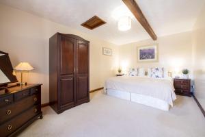 a bedroom with a bed and a dresser and a tv at Corner Cottage in Leyburn