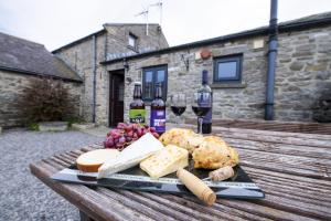 a tray of cheese and wine on a wooden table at Corner Cottage in Leyburn