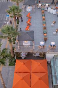 widok na patio ze stołami i pomarańczowymi parasolami w obiekcie Aquila Porto Rethymno w Retimnie