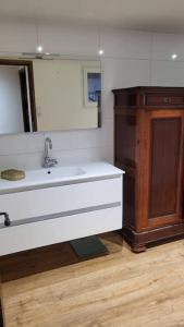 een badkamer met een wastafel en een houten kast bij Gite Volupté 