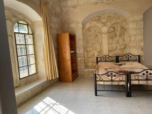 a bedroom with a bed and two windows at Dar Ateeq's Arches/ Bethlehem Apartment in Bethlehem