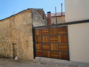 LOS PUENTES casa con jacuzzi para 2 في Olmos de Peñafiel: باب جراج خشبي كبير على جانب المبنى