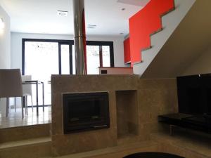 sala de estar con chimenea, TV y escalera. en LOS PUENTES casa con jacuzzi para 2, en Olmos de Peñafiel