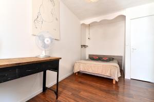 a bedroom with a bed and a desk with a fan at Appartement Les Cigognes du Centre in Colmar