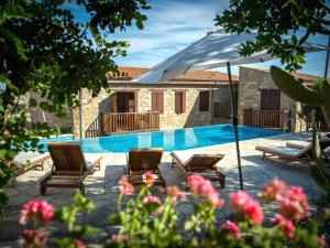 a swimming pool with two chairs and an umbrella at Eveleos Country House in Tochni
